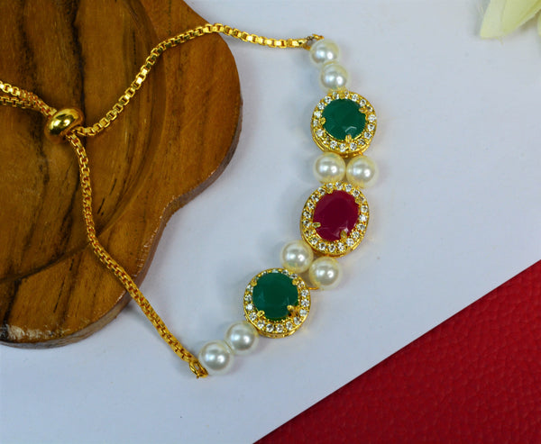 Jewelopia Ruby/Emerald Diamond Studded Gold Plated With Pearl Rakhi Bracelet Adjustable for Women and Girls